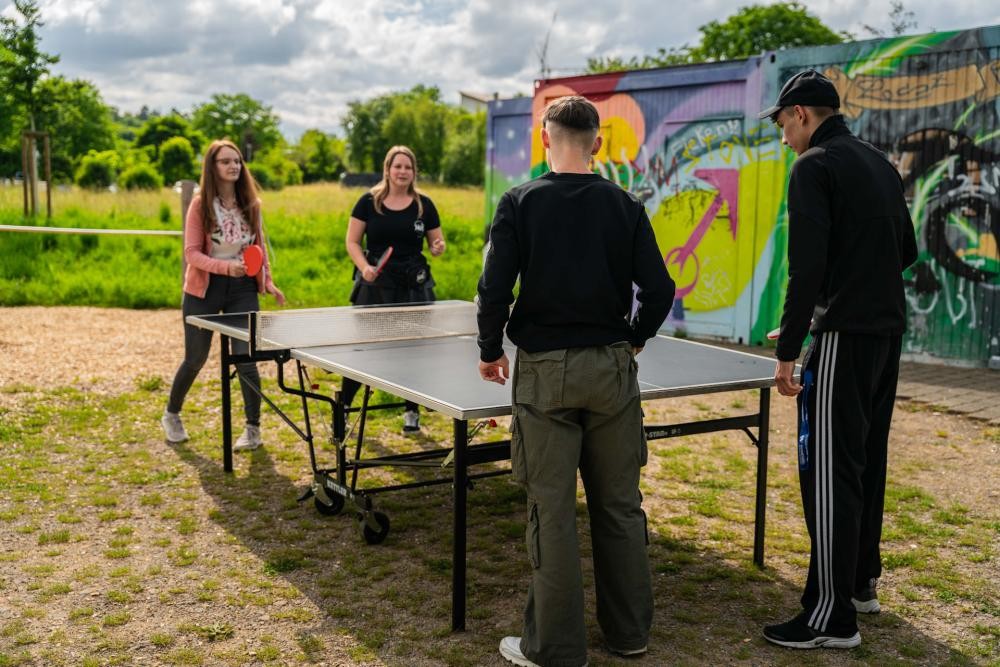 Vier Jugendliche spielen im Freien Tischtennis