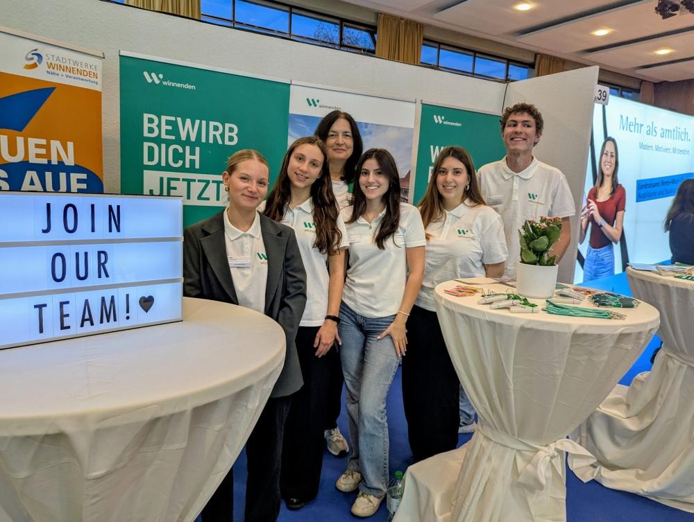 Vier Auszubildende und ein Auszubildender mit Ausbildungsleiterin am Messestand der Stadt Winnenden.