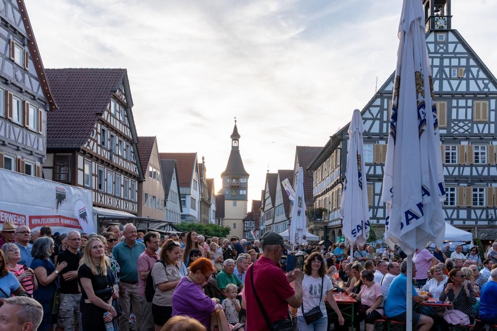 Große Menschenmenge vor Fachwerkhäusern in einer Altstadt mit einem Turm im Hintergrund