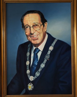 Das Ehrenbürgergemälde zeigt Hermann Schwab im dunkelblauen Anzug mit blauer Krawatte und dünner Brille in lächelnd. Er trägt dabei die Stadtkette mit dem Stadtwappen und den Wappen der Stadtteile um den Hals.