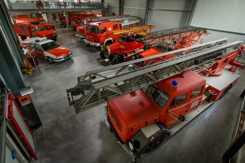 Mehrere alte Feuerwehrautos stehen im Feuerwehrmuseum. Von einem alten Wagen mit Kurbel an der Leiter bis zum Mannschaftswagen sind unterschiedlichste Fahrzeugtypen zu sehen.