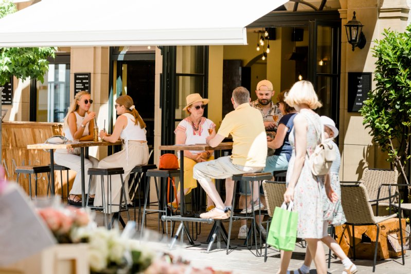 Personen sitzen im Außenbereich eines Cafés in der Marktstraße.