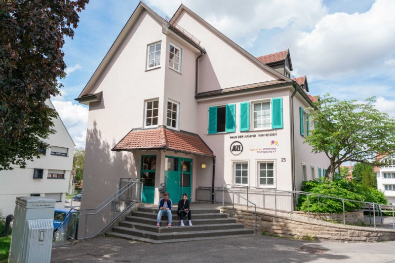 Außenansicht des Juze, dem blasslila Haus mit den türkisen Fensterläden .