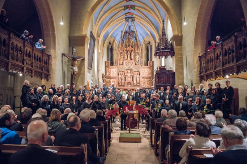 Die Musikerinnen und Musiker stehen vor dem Altar in der Schlosskirche wärend das Publikum auf den Bänken sitzt und klatscht
