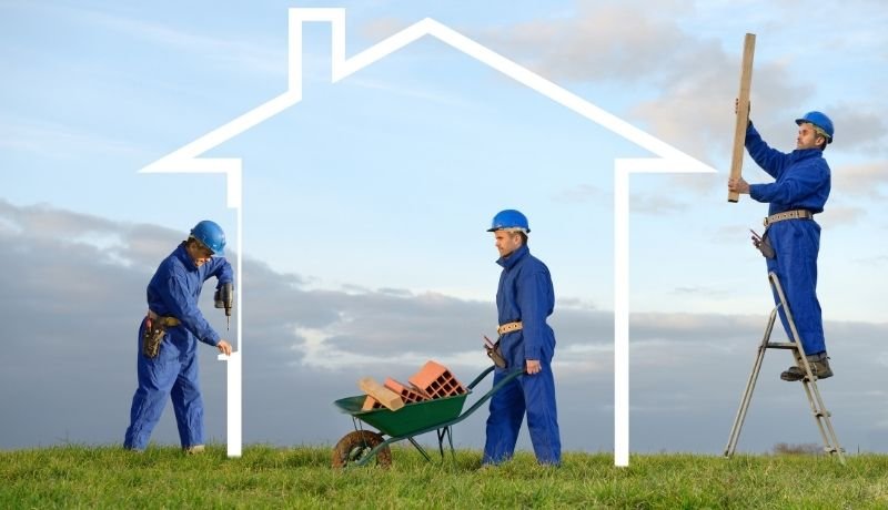 Grafik Drei Bauarbeiter bauen ein den Umrissen eines Hauses auf einer grünen Wiese