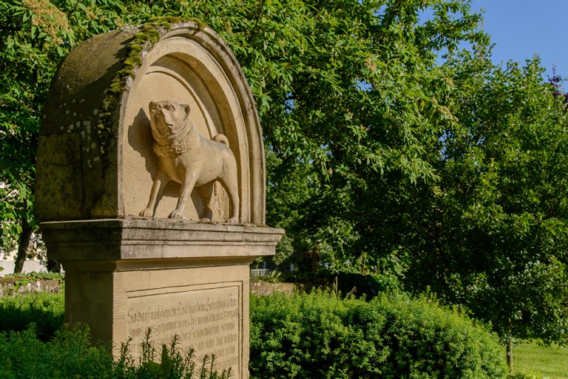 Das Denkmal zeigt die steinerne Figur eines Mops. unter der Figur, im Sockel der Statue, ist die Geschichte des Winnender Mops zu lesen.