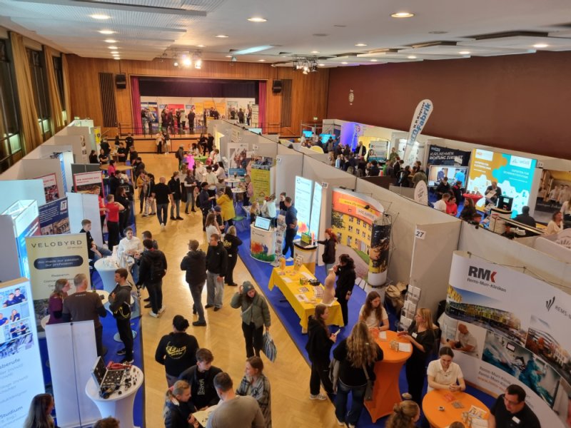 Besucherinnen und Besucher laufen zwischen den Ständen der Unternehmen auf der Ausbildungsmesse in der Hermann-Schwab-Halle