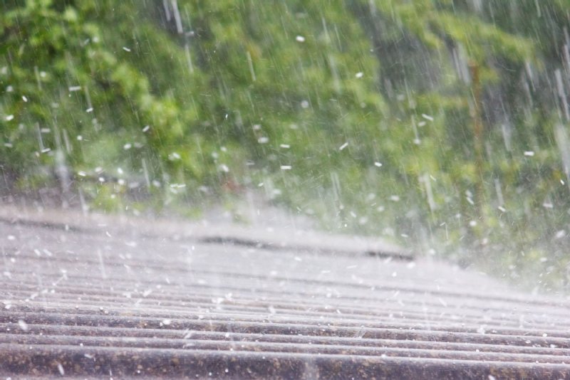 Symbolfoto: Starker Regen fällt auf ein Hausdach