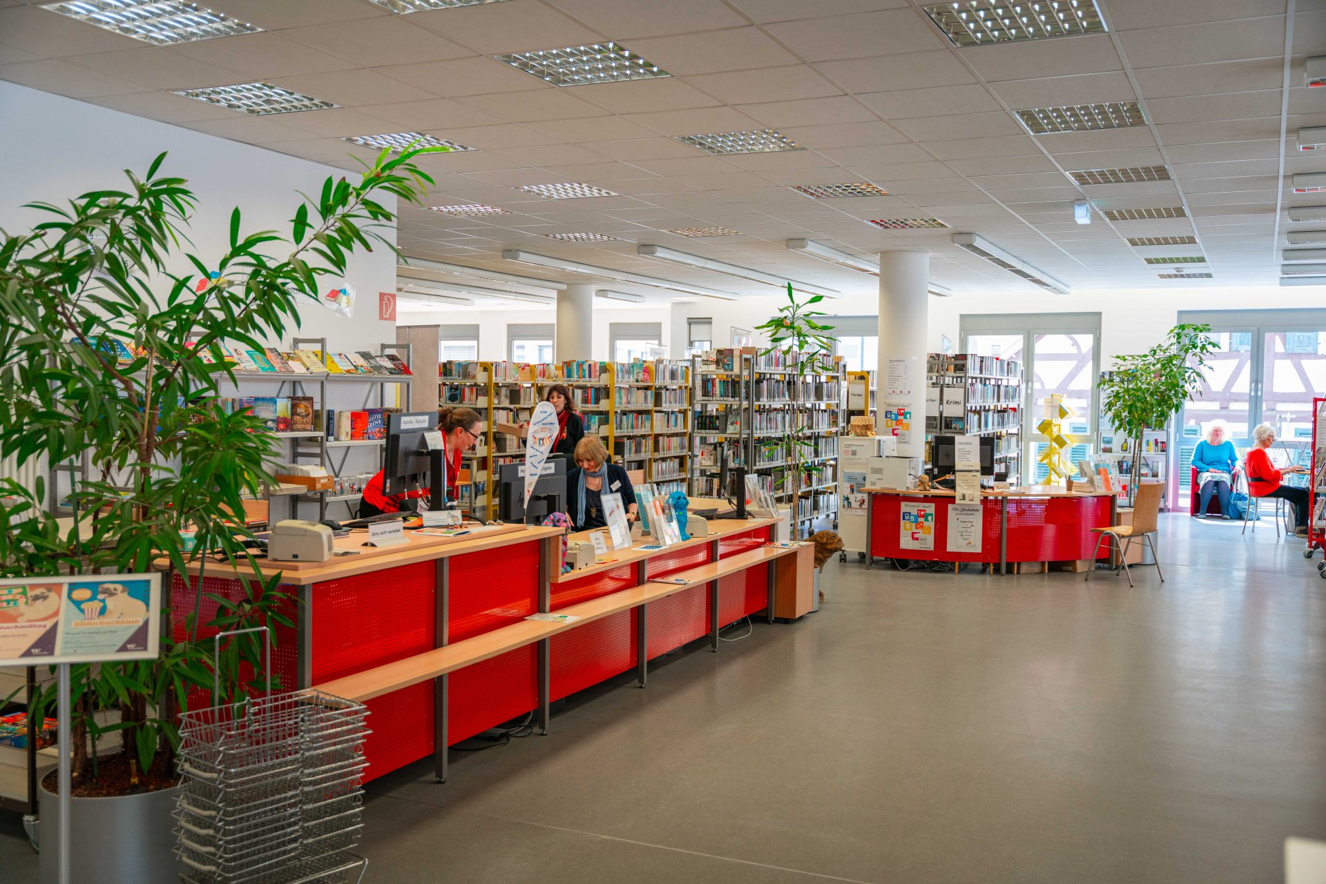 Der Eingangsbereich der Stadtbücherei. Links die Bedientheke und im Hintergrund mehrere Gänge mit Büchern nach Genere geordnet