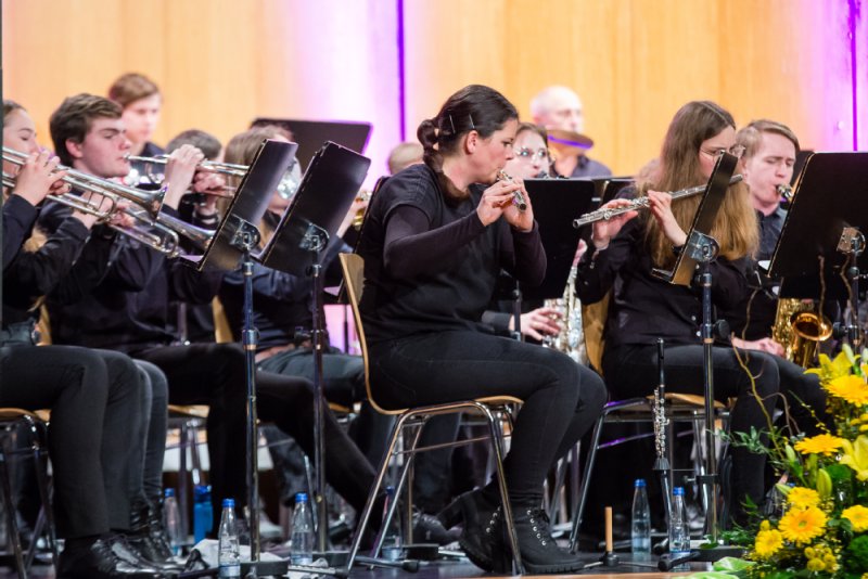 Die Musikerinnen und Musiker spielen auf der Bühne mit Trompete, Querflöte und weiteren Instrumenten