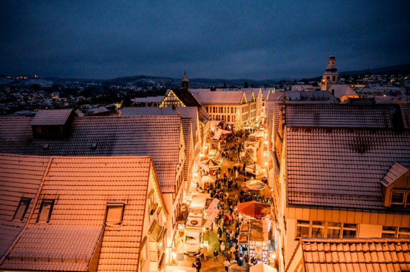 Der Winnender Weihnachtsmarkt vom Torturm aus fotografiert. Man sieht die weihnachtlich beleuchtete Marktstraße mit zahlreichen Ständen und Besuchern.