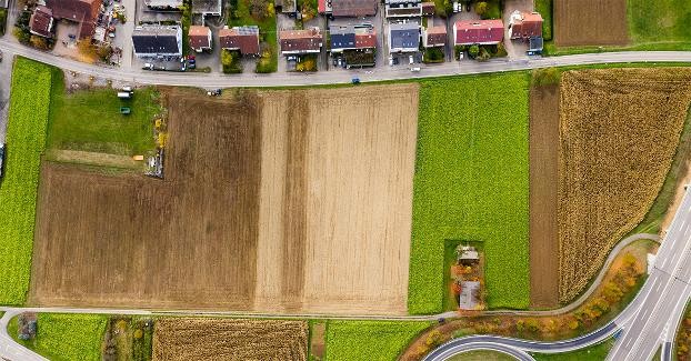Abbildung: Siedlungsrand mit landwirtschaftlichen Ackerflächen und einer Bundesstraße am Bildrand.